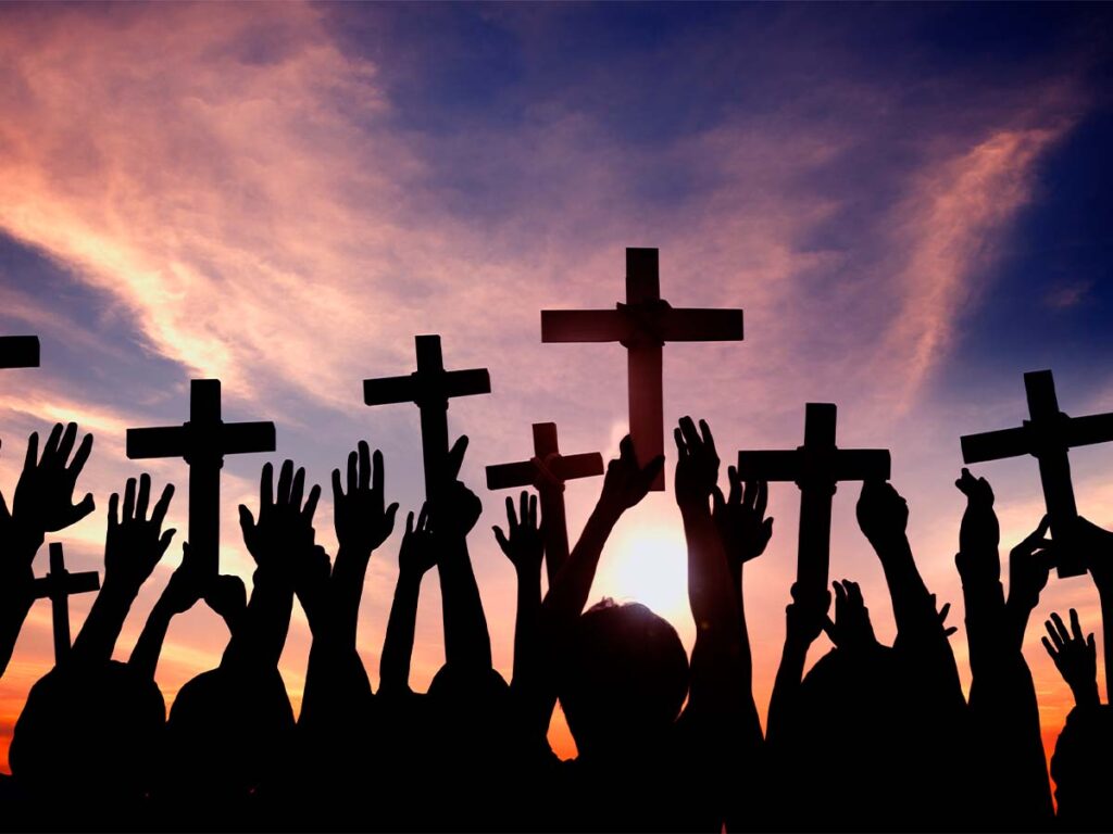 Image of people holding up crosses in sunset
