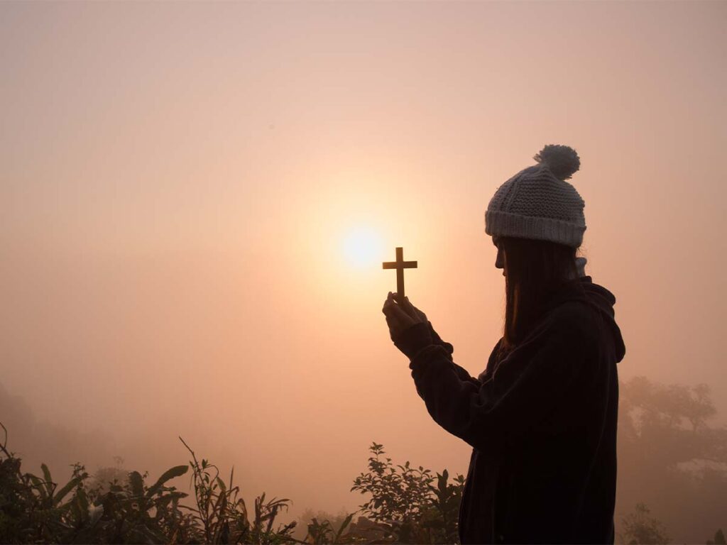 Person holding cross in foggy early morning light